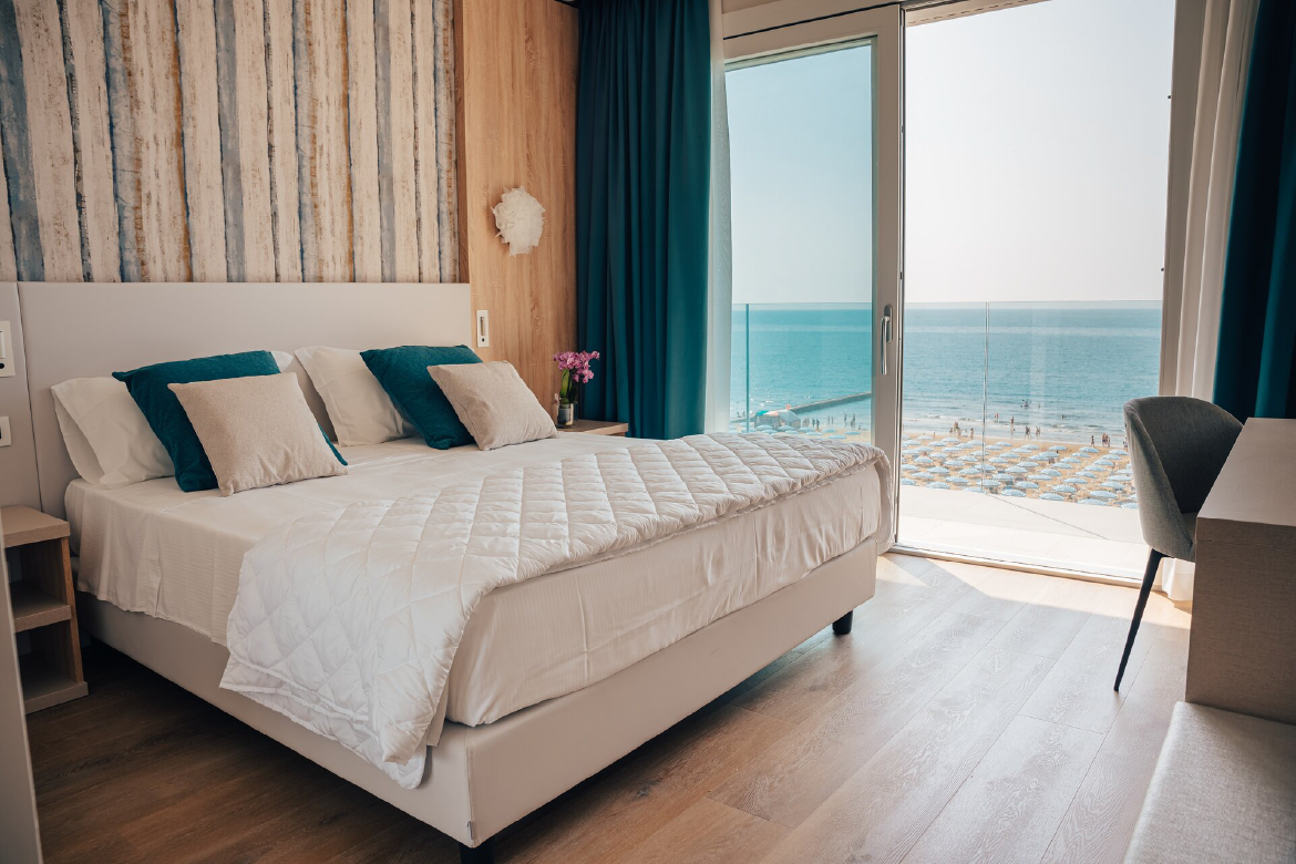 Camera matrimoniale con letto elegante e ampia finestra con vista mare, presso Hotel Galassia, Jesolo